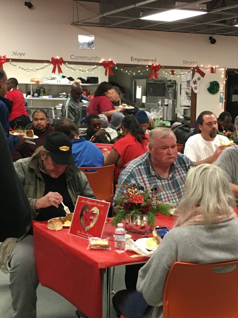 Group of people sitting and enjoying a meal at various tables.